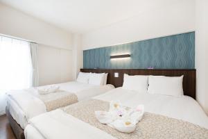 duas camas num quarto de hotel com flores em Ideal Fukushima em Osaka