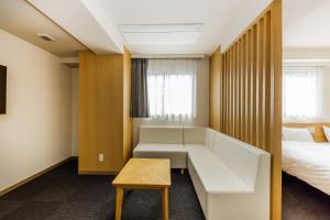 ein Hotelzimmer mit einem Sofa und einem Bett in der Unterkunft HOPETREE OSAKA GRAND in Osaka