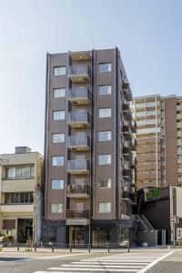 ein hohes Gebäude mit Balkonen auf einem Parkplatz in der Unterkunft HOPETREE OSAKA GRAND in Osaka