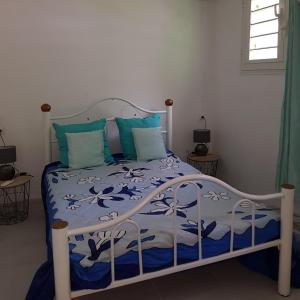 - un lit avec des draps bleus et blancs et des oreillers bleus dans l'établissement LA PERLE MARINE, à Le Prêcheur