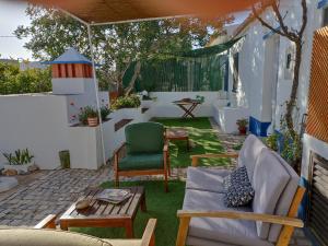 a patio with chairs and a table in a yard at Charming Cottage near Tavira in Juliãos