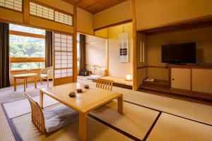 een woonkamer met een tafel en een televisie bij Towada Hotel in Kosaka