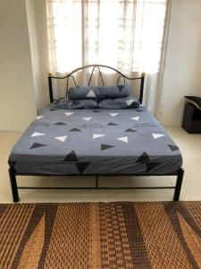 Homestay Chik Da في Kampong Alor Senjaya: سرير مع لحاف أزرق عليه مثلثات بيضاء