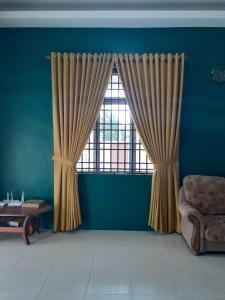 a room with a window with curtains and a chair at Homestay Chik Da in Kampong Alor Senjaya