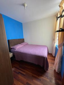 1 dormitorio con 1 cama con sábanas moradas y paredes azules en Exclusivo Apartamento en el corazón de Trujillo en Trujillo