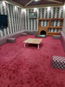 a room with a table and a tv and a red carpet at مزرعة ارياف العلا in Madain Saleh