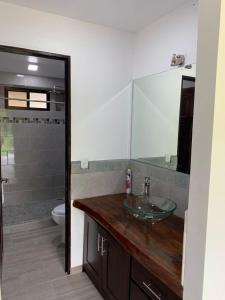 y baño con lavabo de cristal y aseo. en Casa Los Ninos, en Sámara