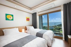 two beds in a room with a large window at Familia Hotel in Seogwipo