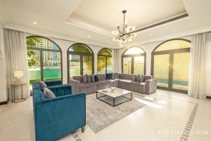 a large living room with couches and a chandelier at LUX - The Savoy Palm Villa in Dubai