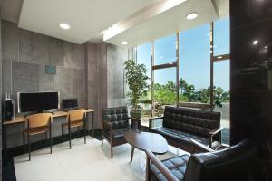 a living room with a couch and a desk with a television at Familia Hotel in Seogwipo