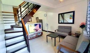 a living room with a staircase with a television and a couch at Kaitleen Home Stay Door 2 in Tacloban