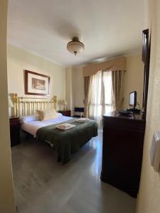 1 dormitorio con cama, escritorio y ventana en fantástico apartamento con parking avenida de cadiz, en Sevilla