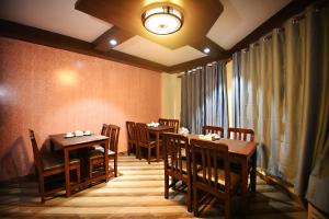 una sala da pranzo con tavoli e sedie e una finestra di Karma Hotel Nepal a Kathmandu