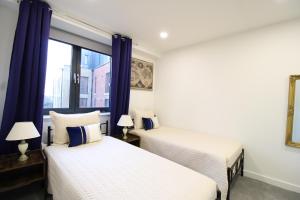 dwa łóżka w pokoju z oknem w obiekcie Virexxa Bedford Centre - Premier Suite - 2Bed Flat with Free Parking & Gym w mieście Bedford
