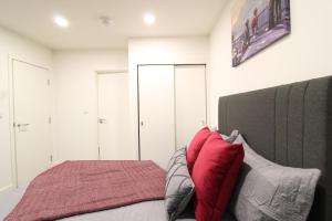 sypialnia z łóżkiem z czerwonymi poduszkami w obiekcie Virexxa Bedford Centre - Premier Suite - 2Bed Flat with Free Parking & Gym w mieście Bedford