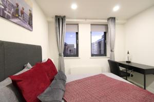 a bedroom with a bed and a desk and windows at Virexxa Bedford Centre - Premier Suite - 2Bed Flat with Free Parking & Gym in Bedford