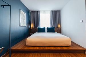a bedroom with a large bed with blue walls at QUU HOTEL Chiang Mai in Chiang Mai