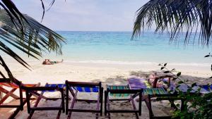 a person sitting in a chair on a beach at Phi Phi Relax Beach Resort in Phi Phi Islands