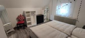 ein Schlafzimmer mit einem Bett und einem Stuhl und einem Fenster in der Unterkunft Haus Kunterbunt in Mehlingen