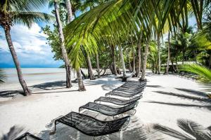 a row of lounge chairs on a beach with palm trees at Siam Royal View Pool Villa in Ko Chang