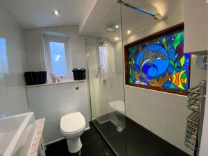 uma casa de banho com um WC e um vitral. em Rooms At Babbacombe em Torquay