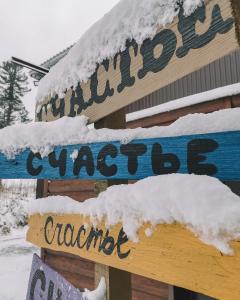 a snow covered sign for a quilting cottage at Apart-hotel Schastye in Sheregesh