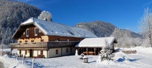 uma grande casa de madeira na neve com montanhas em Landhaus Algerhof em Abtenau