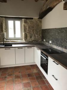 cocina con armarios blancos, fregadero y ventana en Gîte loustalneve, en Bourg-de-Visa