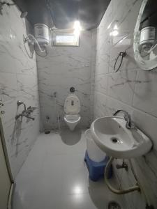 La salle de bains blanche est pourvue d'un lavabo et de toilettes. dans l'établissement CASA Orchard House, à Mount Âbû