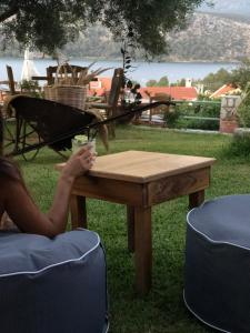 a woman sitting at a wooden table with a drink on it at Liostasi Retreat in Argostoli