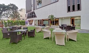 un groupe de tables et de chaises sur l'herbe devant un bâtiment dans l'établissement Treebo Trend Kanopy Greens, à Dehradun