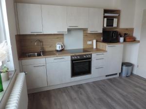 a kitchen with white cabinets and a sink at Ferienwohnung Landblick in Homberg