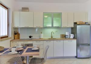 a kitchen with white cabinets and a table with chairs at Apartments Leona in Umag