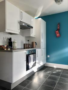 uma cozinha com armários brancos e uma parede azul em Tudors em Chelmsford