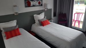 two beds in a hotel room with red pillows at Hotel du Porge in Le Porge