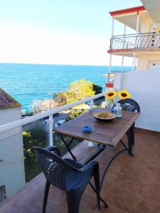 una mesa de madera y sillas en un balcón con vistas al océano en Ca la Nuri Pis 2 con Vistas al Mar, en Llançà