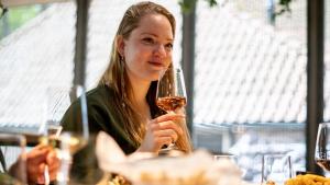une femme assise à une table tenant un verre de vin dans l'établissement Nobel Hotel Ameland, à Ballum