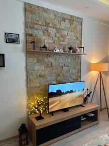 ein Wohnzimmer mit einem Flachbild-TV auf einem Steinkamin in der Unterkunft Milmari Apartman Haski N55 in Kopaonik
