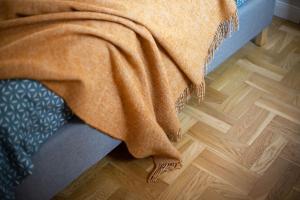 an orange blanket on a bed on a wooden floor at Art & Comfort Home in Kaunas