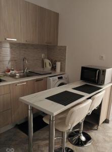 uma cozinha com uma mesa, um micro-ondas e um lavatório em Aphrodite Studio near Athens Floisvos Marina em Atenas