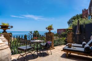 a patio with a table and chairs and the ocean at Hotel Villa Carlotta in Taormina