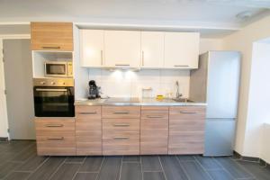 a kitchen with wooden cabinets and a refrigerator at F2 101 neuf proche gare TGV, A36 et commerces in Botans