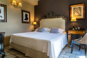 a bedroom with a large white bed and a table at Hotel Villa Carlotta in Taormina