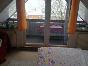 Zimmer mit einem Balkon mit einem Tisch und Fenstern in der Unterkunft Hoernchens-Ferienwohnung in Neuenkirchen