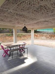 a picnic table and two red chairs under a pavilion at Villa Coco avec jardin piscine et terrain de boules de 180 m carrés in Les Arcs sur Argens