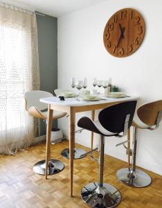 a table with chairs and a clock on the wall at Proche Lac & vieille ville T3 avec grande terrasse in Annecy +12 photos