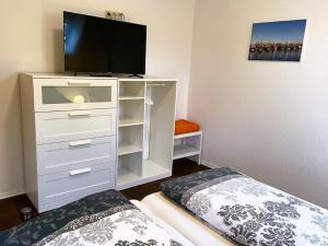 een slaapkamer met een witte dressoir en een flatscreen-tv bij Weideblick in Upgant-Schott