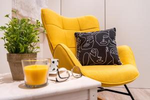 Lemon Suite - Fiera Milano - City Life في ميلانو: كرسي أصفر وكأس عصير برتقال على طاولة