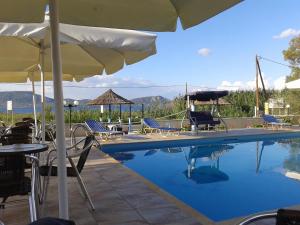 una piscina con sillas y sombrilla en Villa Chrisanthi, en Gera