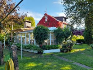 een huis met een rood dak met planten in de tuin bij Casa Rural A Capela Carracido in Porriño